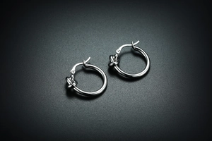 Vue macro de boucles d'oreilles créoles nouées argentées au fini métallique poli