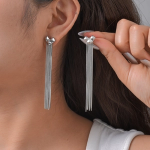 Gros plan de boucles d'oreilles cœur argentées avec de longues franges sur le modèle