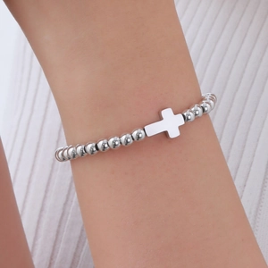 Bracelet à billes en acier inoxydable poli avec pendentif croix porté par un modèle