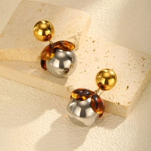 Close-up of vintage geometric earrings with gold spheres and tortoiseshell resin details