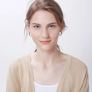Gros plan de boucles d'oreilles créoles dorées nouées montrant la texture sur un modèle