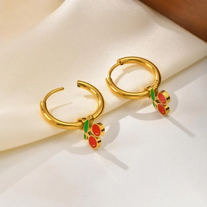 Vue macro des boucles d'oreilles créoles cerise dorées avec émail rouge et feuilles vertes