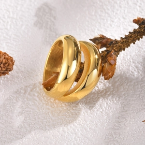 Close-up of two polished gold geometric rings displayed on natural wood branches