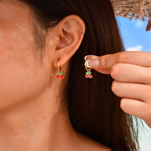 Gros plan de jolies boucles d'oreilles cerises avec fruits rouges et feuilles vertes sur mannequin