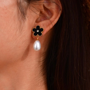 Close-up of elegant black flower drop earrings with white teardrop pearls and gold trim