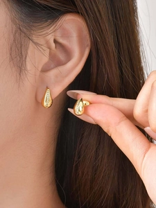 Close-up of vintage golden teardrop earrings with pavé zircon worn on a female ear