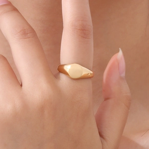 Gros plan d'une bague chevalière en or poli avec un plateau rond porté au doigt