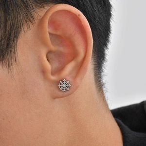 Close-up of a silver stainless steel spider web stud earring worn on a male earlobe