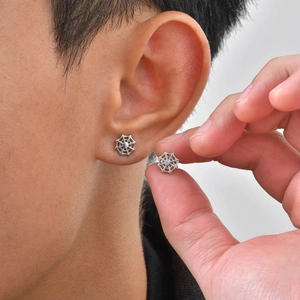 Detailed close-up of punk style stainless steel spider web stud earrings worn on ear