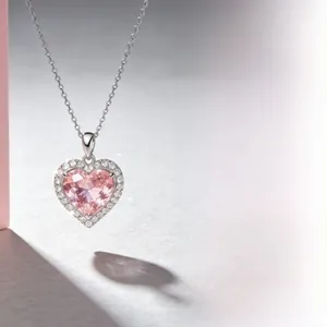 Macro shot of silver heart-shaped pink gemstone pendant with detailed diamond halo