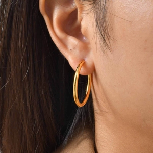 Close-up of polished gold-plated hoop earrings on a model for actual size reference