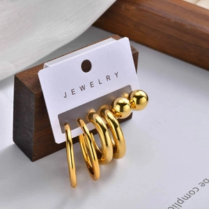 Detailed set of five polished gold earrings including hoops and ball studs on display