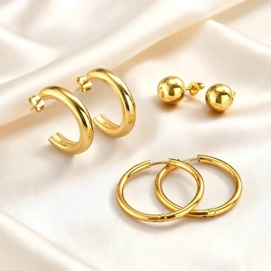 Detailed set of three gold-plated stainless steel earrings on elegant silk fabric