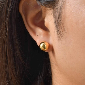 Close-up of a polished gold ball stud earring worn on the ear for a minimal style