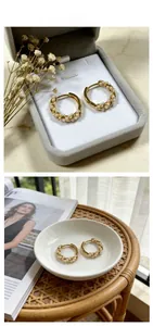 Detailed view of twisted gold hoop earrings with small pearls on grey velvet jewelry box