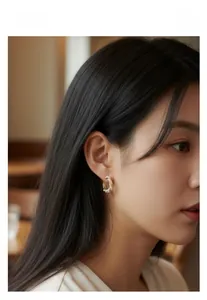 Close-up of golden hoop earrings with small pearls worn by a model for elegant styling