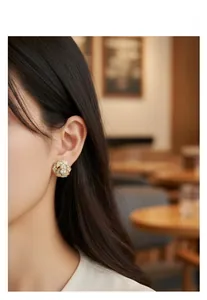 Close-up of elegant gold rose stud earrings with pavé crystals worn by a female model