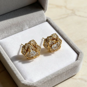 Rotating crystal rose stud earrings with gold plating and paved stones in jewelry box