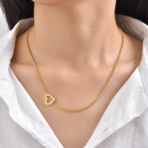 Dettaglio della collana minimalista dorata con ciondolo a cuore su camicia bianca