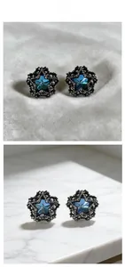 Detail of gothic star stud earrings with blue faceted crystal and black carved metal frame