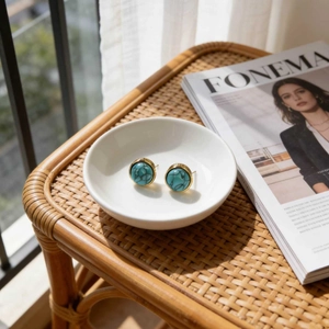 Vintage round turquoise stud earrings in gold metal base on a white ceramic bowl
