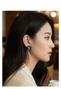Close-up of star stud earring with blue center stone and black diamond halo on ear