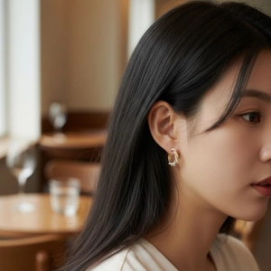 Elegant Mobius gold hoop earrings with small pearls shown on a female model for daily wear