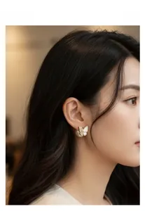 Detailed view of elegant gold butterfly stud earring with mother-of-pearl and pearl backing