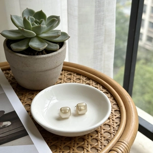 Elegant gold-plated square pearl earrings on a white porcelain tray in home setting