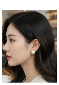 Close-up of star-shaped earrings with gold plating and zircons on a model's ear