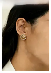Detailed close-up of a vintage gold-plated star compass stud earring worn by a model