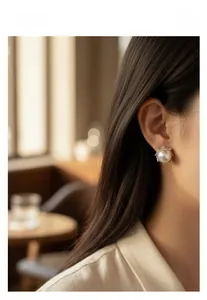 Detail of elegant pearl crown earrings with rhinestones on model in soft cafe lighting