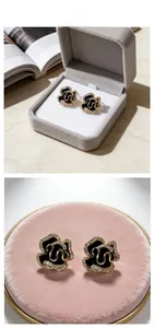 Macro detail of enamel camellia stud earrings with rhinestones on a velvet base