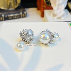 Detailed macro shot of double pearl earrings with silver crown setting and pave crystals