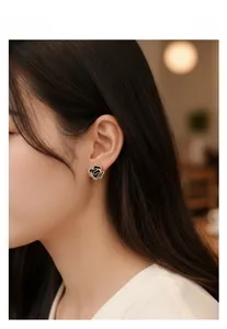 Detailed view of enamel camellia stud earrings with a gold snake pattern and zircon rim