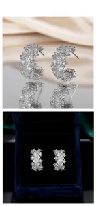 Detail of luxury C-shaped silver earrings with sparkling zircons and velvet gift box