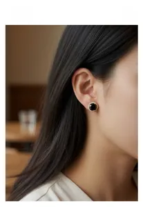 Détail des boucles d'oreilles rondes avec pierre noire et bordure dorée sertie de zircons