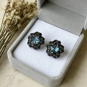 Blue star black diamond stud earrings with silver setting on grey velvet jewelry box