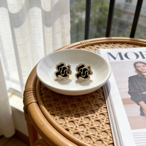 Classic camellia stud earrings in gold and black enamel featuring sparkling white crystals