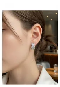 Close-up of a silver-toned C-shaped earring with pavé crystals worn by a model