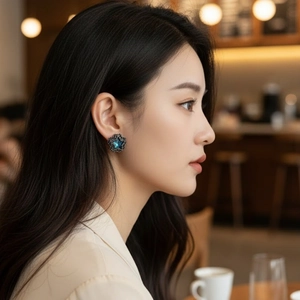 Star-shaped blue stone stud earrings with black diamond accents worn by a model