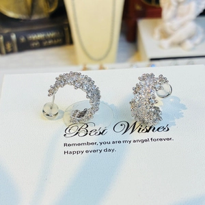 Detail of silver C-shaped earrings with micro-paved clear zircons on display card