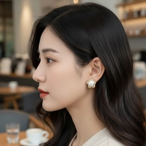 Elegant gold-plated star earrings with mother of pearl inlay worn by a female model