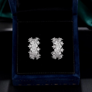 Elegant silver hollow floral stud earrings with pavé stones on a premium jewelry box