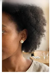 Detailed close-up of a vintage round stud earring with turquoise stone on a female model