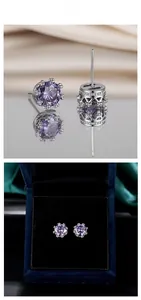 Détail macro de boucles d'oreilles couronne violettes dans une boîte à bijoux en velours bleu