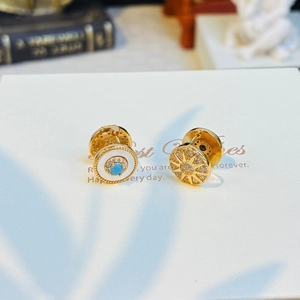 Macro view of gold stud earrings featuring a blue stone eye and sunburst crystal star
