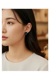 Close-up of retro navy blue zircon stud earrings worn by a model in a warm setting
