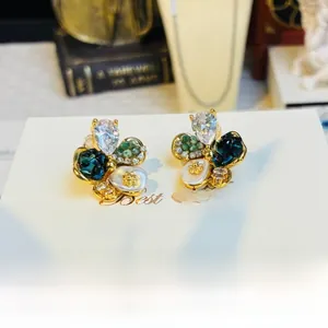 Macro shot of vintage crystal floral earrings with emerald gems and pearl accents