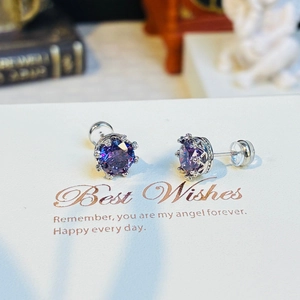 Détail de boucles d'oreilles en cristal violet avec serti couronne sur une carte